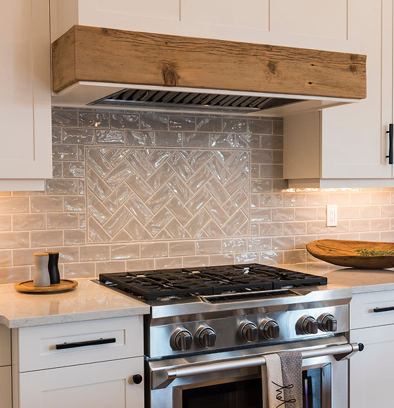 Custom kitchen with a reclaimed wood range hood and herringbone tile backsplash
